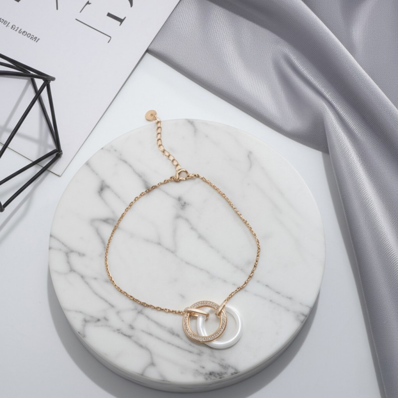 Bracelet fantaisie deux anneaux entrelacés femme carador en plaqué or avec oxydes de zirconium et céramique blanche