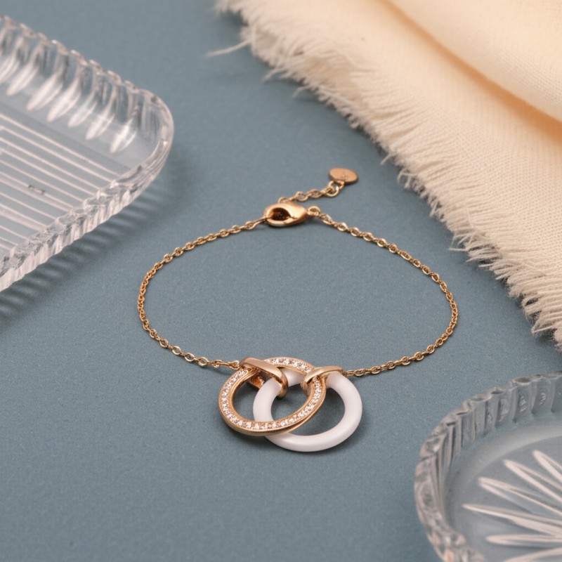 Bracelet fantaisie deux anneaux entrelacés femme carador en plaqué or avec oxydes de zirconium et céramique blanche